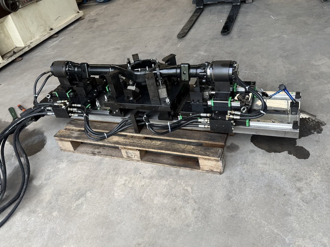 Complete axle housing fixture on a sub-plate, ready for crating &mdash; hydraulic clamps, floating supports and hose routing in place